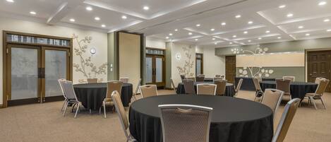 A conference room with round tables, chairs, and a ceiling with recessed lighting.