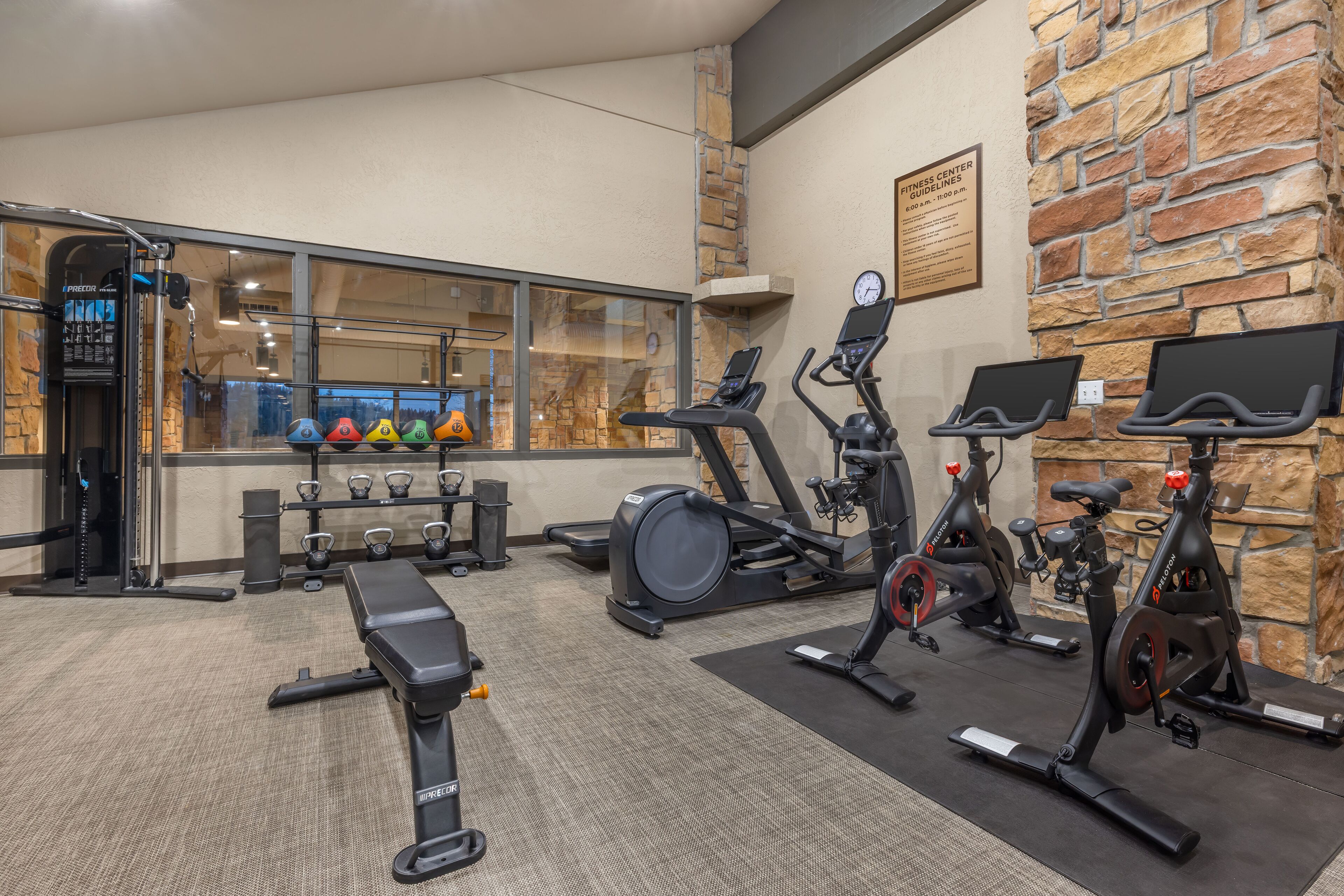 Un gimnasio con equipo de ejercicio, una banca y un reloj de pared.
