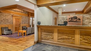 A reception area with a stone wall, wooden reception desk, and seating area with striped chairs. - Hilton Vacation Club Cedar Breaks Brian Head (Brian Head)