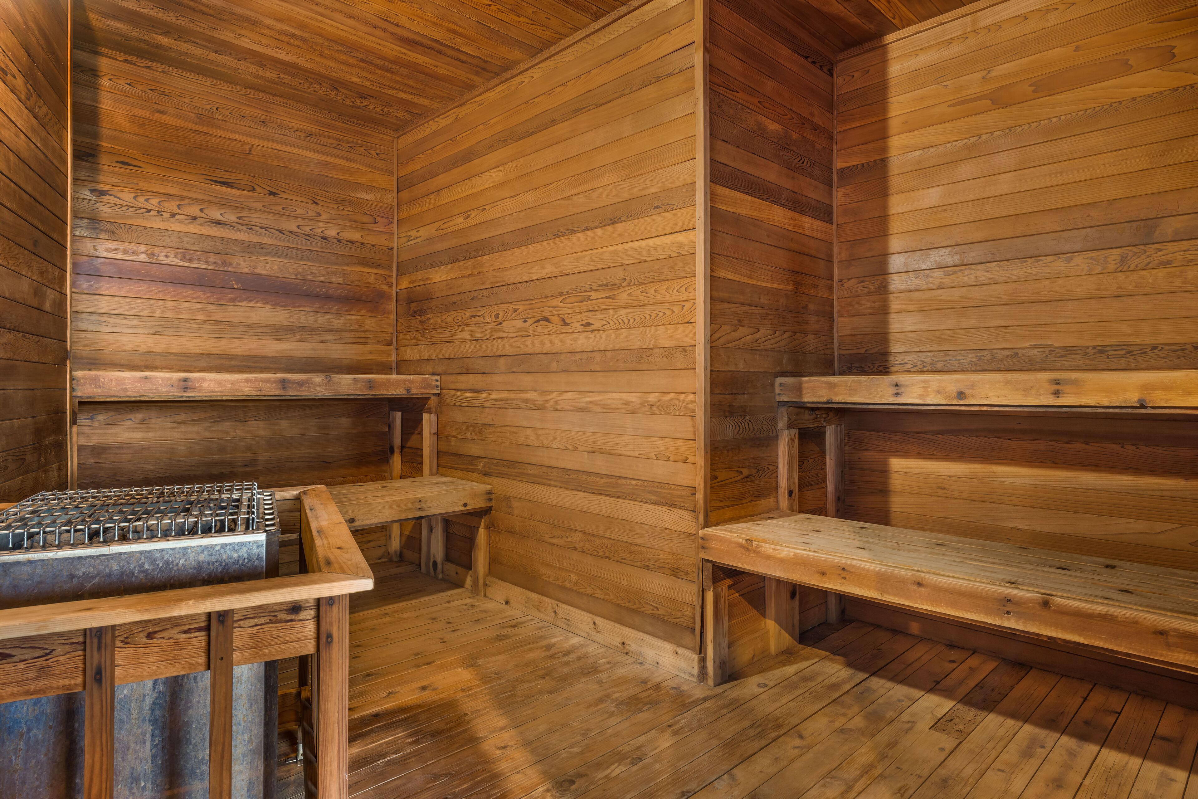 A wooden sauna with benches and a metal heating element.