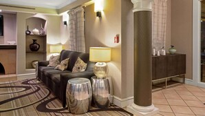 A modern living room with a sofa, two lamps, a decorative rug, and a column. - Travelodge by Wyndham Golden/Denver (Wheat Ridge)
