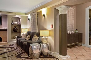 A modern living room with a sofa, two lamps, a decorative rug, and a column. - La Quinta Inn by Wyndham Denver Golden (Wheat Ridge)