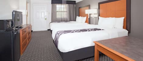 A hotel room with two beds, a desk, a TV, and a dresser.