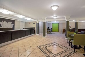 A hotel lobby with a reception desk, seating area, and a patterned floor.