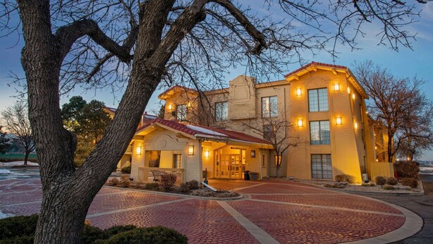 A hotel with a brick facade, a red-tiled roof, and a paved driveway. - Travelodge by Wyndham Golden/Denver (Wheat Ridge)
