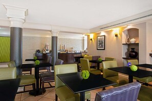 A restaurant with tables and chairs, a bar area, and a wall with a framed picture.