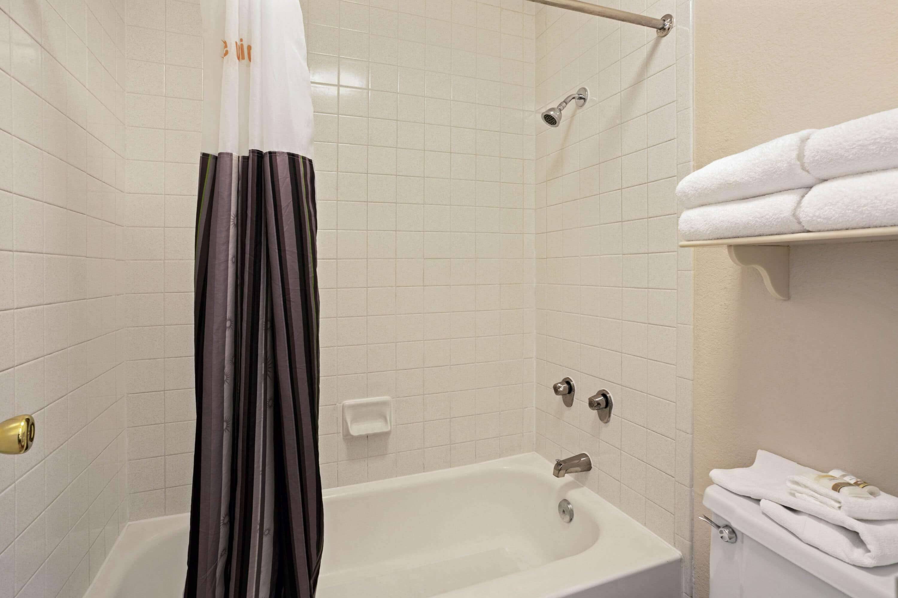 A bathroom with a bathtub, a shower curtain, a towel rack, and a toilet.