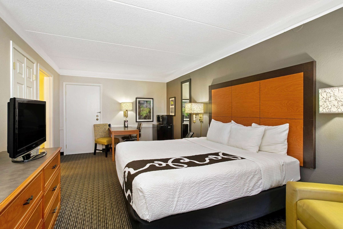 A hotel room with a bed, a television, a desk, and a chair.