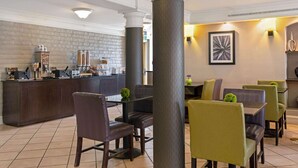 A restaurant area with a bar, chairs, and a table. - Travelodge by Wyndham Golden/Denver (Wheat Ridge)