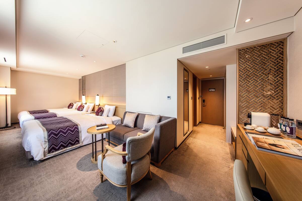 Quarto de hotel com cama, sofá, escrivaninha e cadeira.