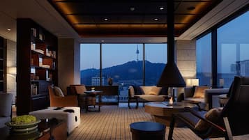 Enjoy a panoramic view of the city and mountains from the large window, with a comfortable seating area and well-organized bookshelf.