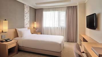 Quarto de hotel com uma cama grande, mesas de cabeceira, uma televisão de tela plana e uma escrivaninha com cadeira.