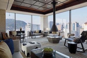 Une chambre d’hôtel moderne offrant une vue imprenable sur la ville, un coin salon confortable et une table centrale originale.