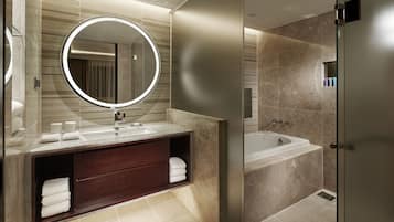 A modern bathroom with a large mirror, a double sink vanity, a bathtub, and a walk-in shower.