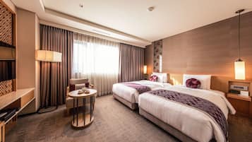 A hotel room with two beds, a TV, a small table, and a sofa.