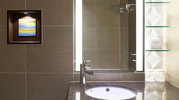 A bathroom with a granite countertop sink, a mirror, and a framed artwork.