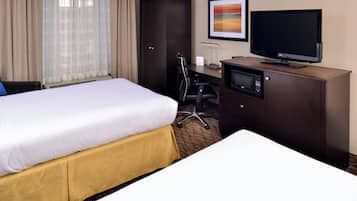 A hotel room with a bed, a desk with a television, a wardrobe, and a chair.