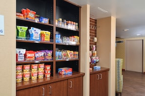 A snack and pantry area with shelves stocked with various food items like chips, crackers, and canned goods.