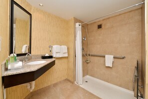 A modern bathroom with a granite countertop sink, a large mirror, a walk-in shower with a glass door, and a towel rack. - Holiday Inn Express Hunt Valley by IHG (Hunt Valley)