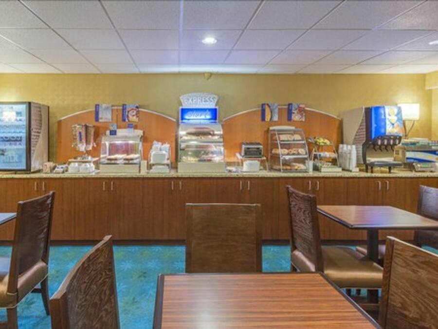 A hotel dining area with a self-service breakfast bar, seating arrangements, and a sign indicating a room for express service.