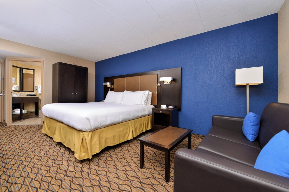 A hotel room with a bed, a desk, a chair, and a nightstand.