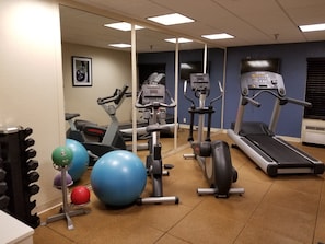 A gym with various exercise equipment including treadmills, an elliptical, and exercise balls.
