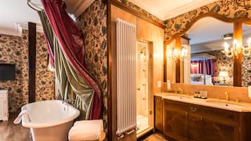 Un baño clásico con una bañera independiente, un tocador de madera y un espejo grande.
