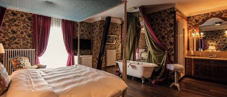 A room with a large bed, a bathtub, and a vanity with a mirror.