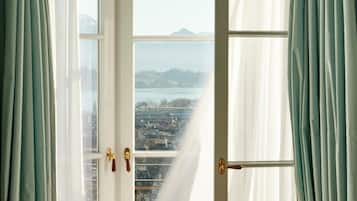 Una habitación con un ventanal, cortinas y vistas a la ciudad y montañas.