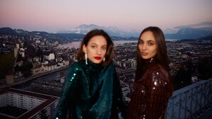 Two individuals standing on a balcony overlooking a cityscape with mountains in the background. - Chateau Guetsch (Lucerne)