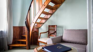 A wooden staircase, a wooden chair, a grey sofa, and a glass coffee table with a book.