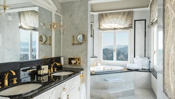 A luxurious bathroom with two sinks, a large mirror, and a view of the mountains.