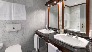 A modern bathroom with two sinks, a toilet, and a large mirror.