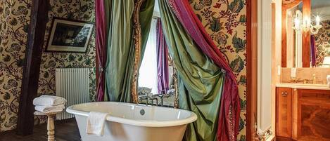 Ein Badezimmer mit freistehender Badewanne, einem Holzbadezimmer-Möbelstück und einem Spiegel.