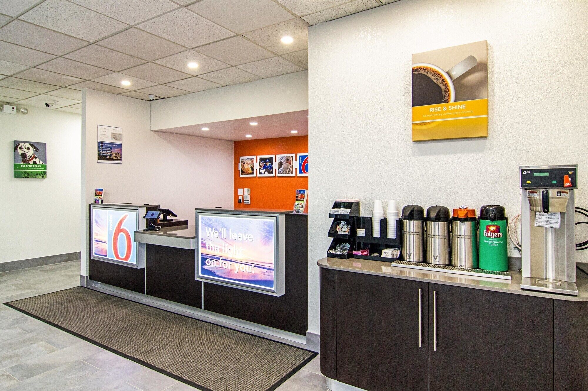 A coffee station with a digital display, a coffee machine, and a variety of coffee cups and mugs.