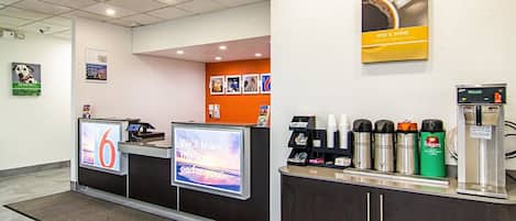A coffee station with a digital display, a coffee machine, and a variety of coffee cups and mugs.
