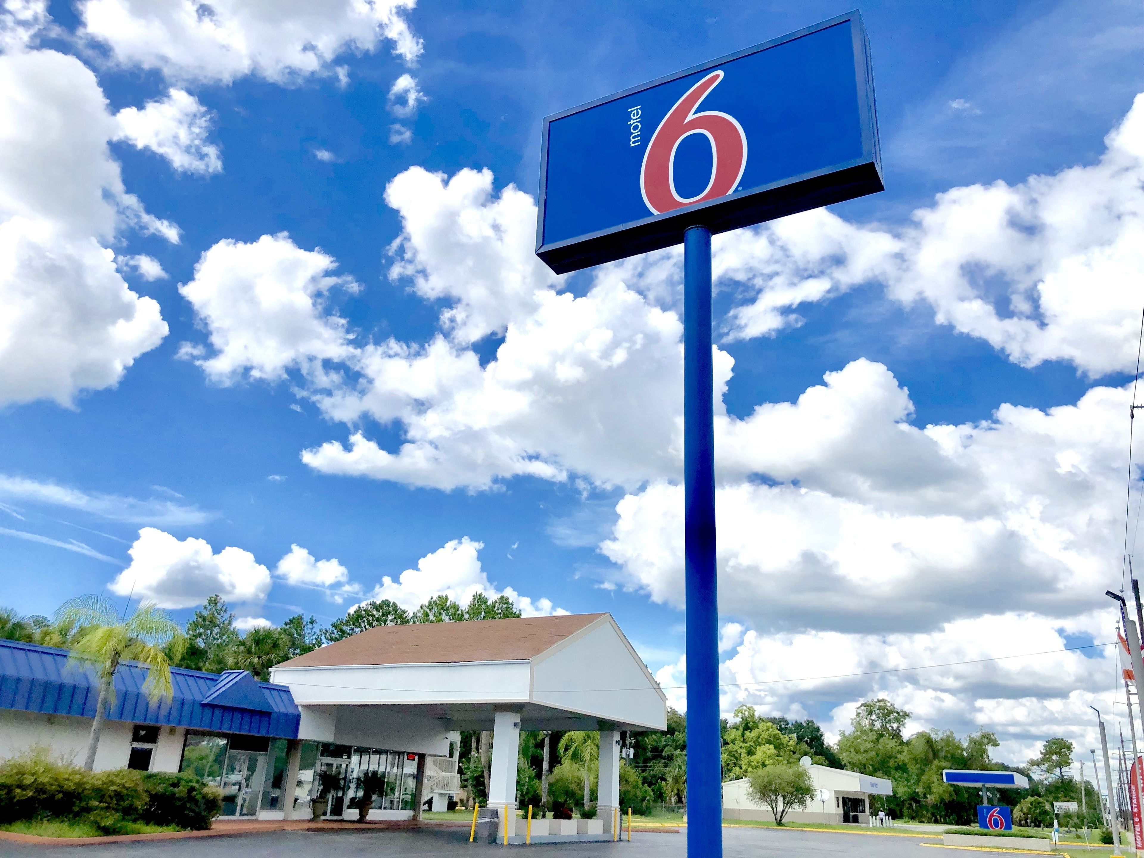 A motel sign with the number 6, a gas station, and a building with a white roof.