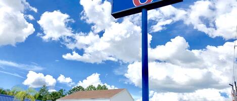 Un panneau indiquant un motel avec le chiffre 6, une station-service et un bâtiment avec un toit blanc.