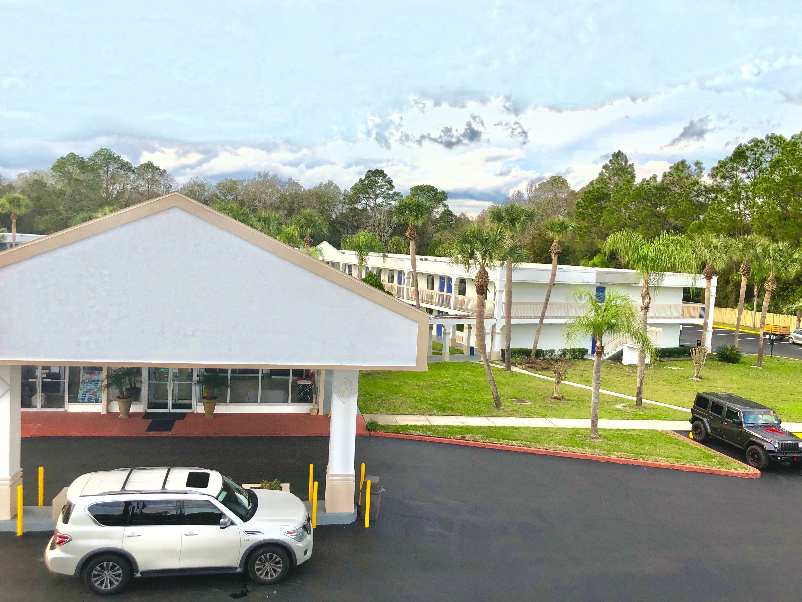 A hotel with a white building and a parking area.