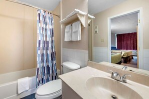 A bathroom with a toilet, sink, and shower curtain.