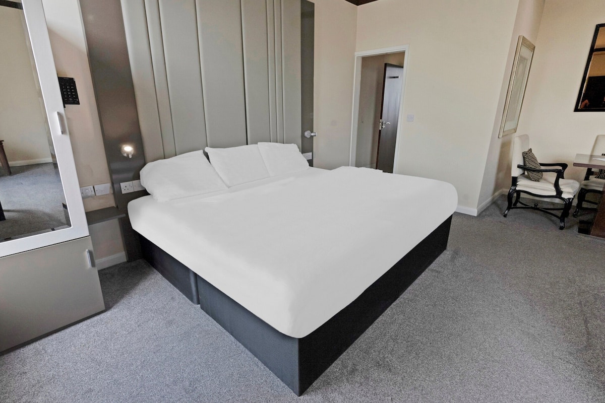 Ett modernt hotellrum med en stor säng, ett skrivbord med en stol och en garderob.