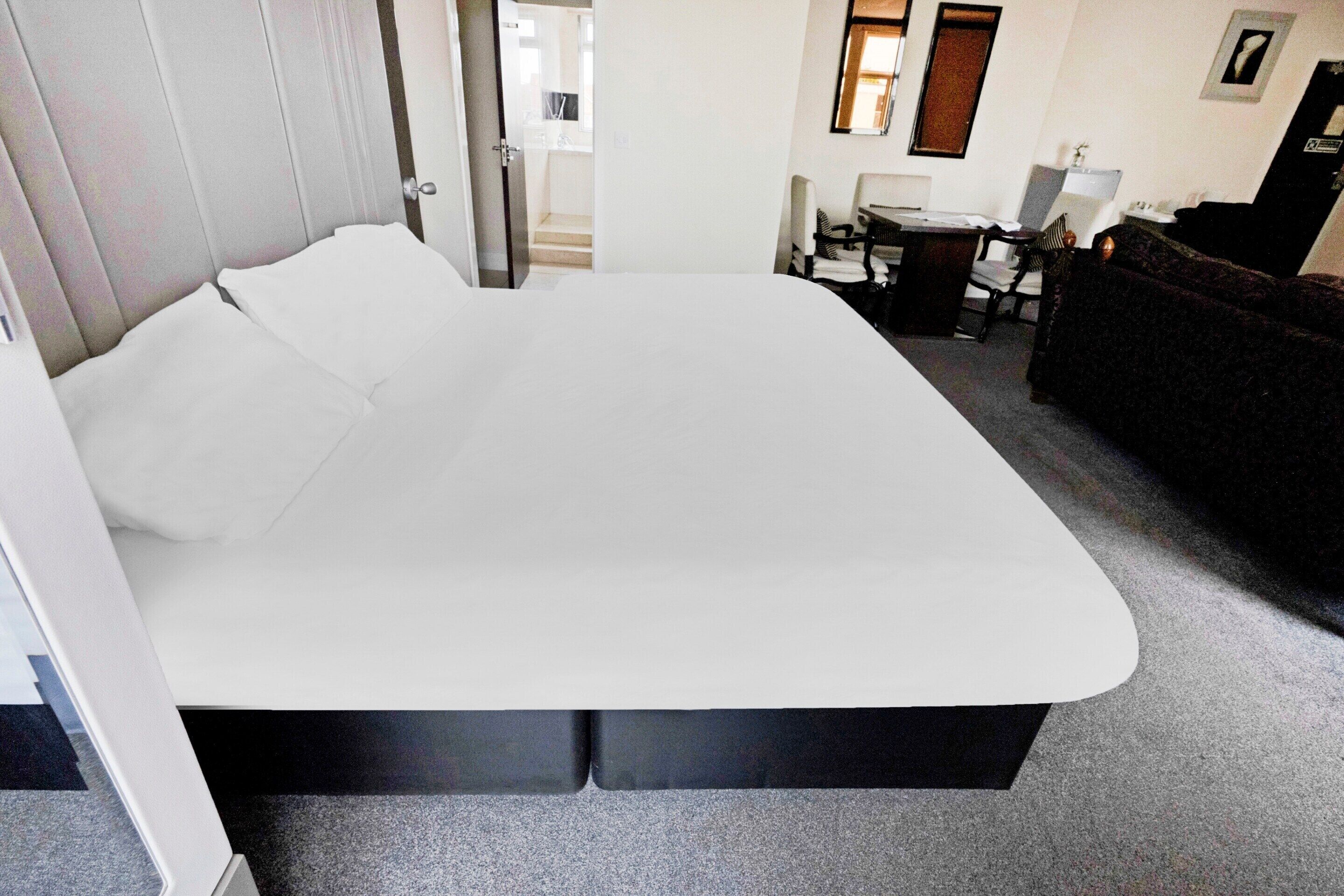 A room with a large bed, a desk, and a chair.