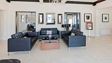 A spacious living area with a black leather sofa set, a wooden coffee table, and a chandelier.