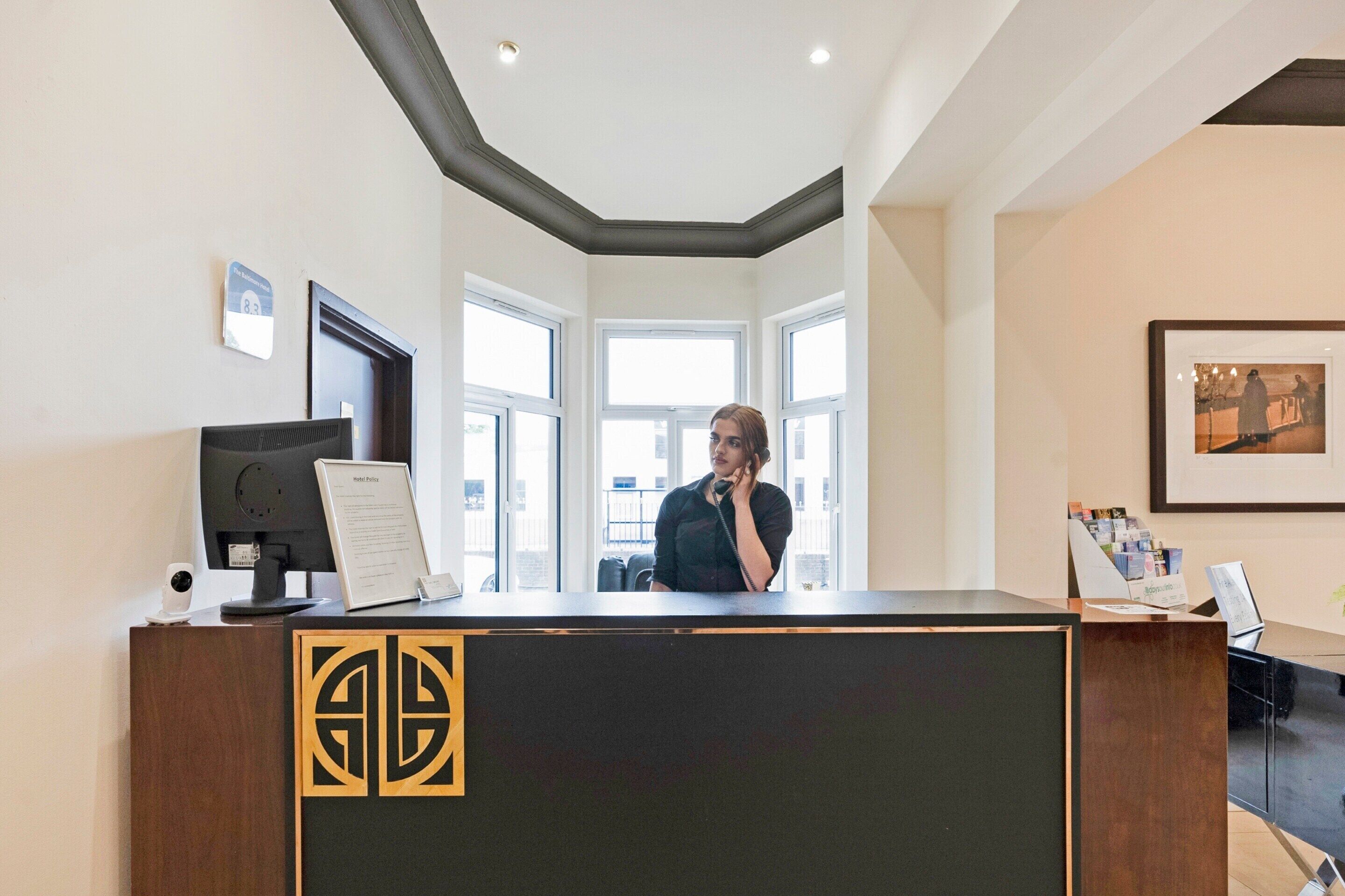 A reception desk with a modern design, a computer, and a framed welcome sign.