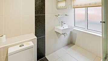 A modern bathroom with a toilet, sink, and shower area.