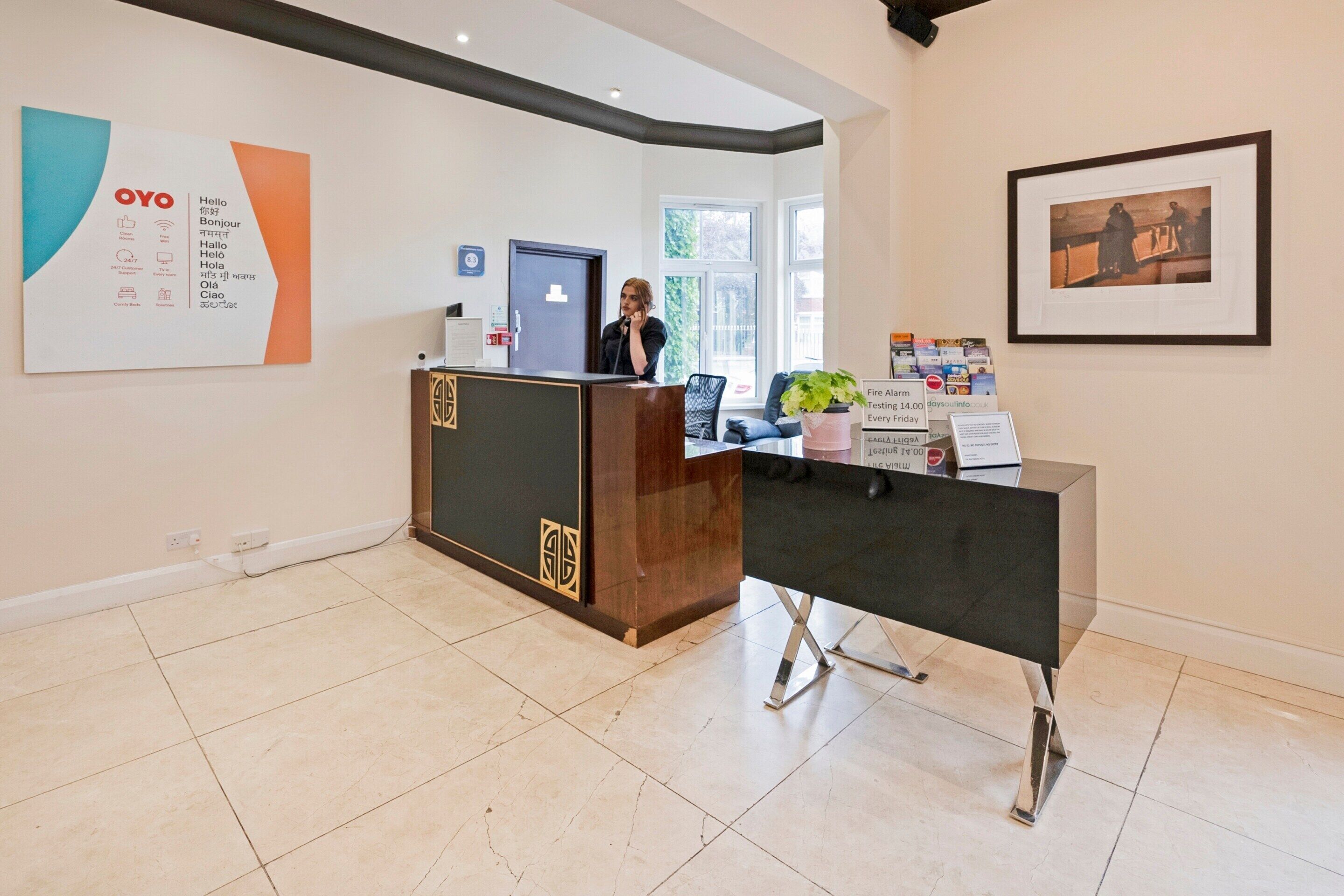 A reception area with a wooden desk, a framed picture on the wall, and a large OYO multilingual sign.