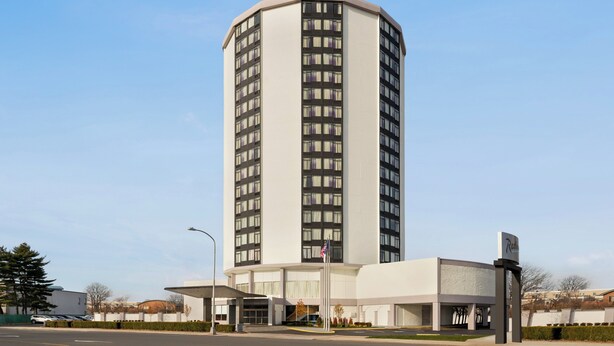 A tall, modern hotel with a curved facade, a prominent entrance, and a flagpole. - Holiday Inn Philadelphia Arpt-Stadium Area by IHG (Philadelphia)