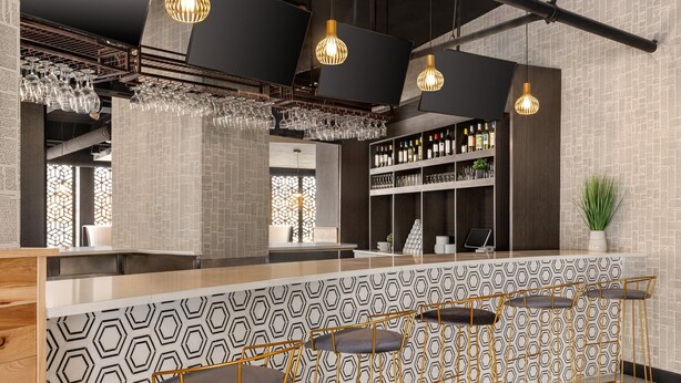 A bar area with hexagonal patterned walls, a counter with stools, and hanging light fixtures.