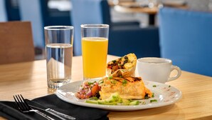 A breakfast setting with a plate of food, two glasses of orange juice, and a white cup on a wooden table. - Holiday Inn Philadelphia Arpt-Stadium Area by IHG (Philadelphia)