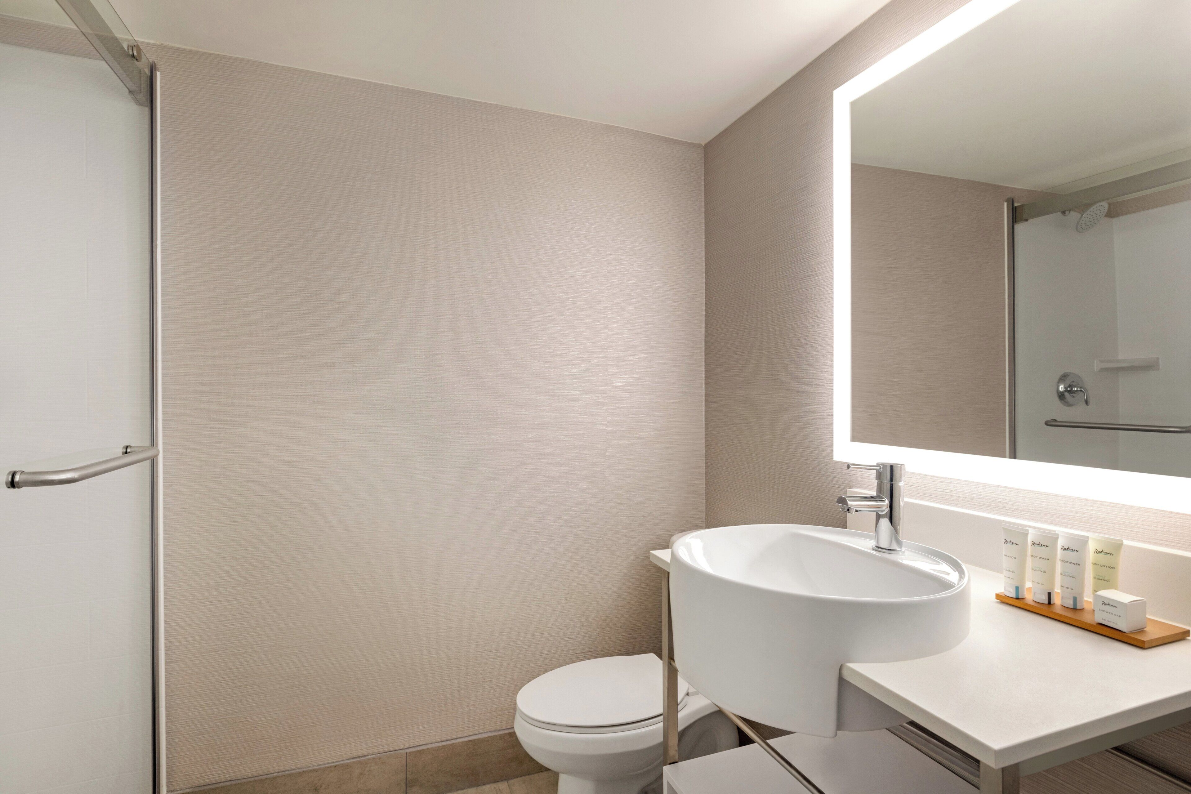A modern bathroom with a white sink, a toilet, and a shower area.